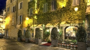A historic building with ivy-covered walls, a red carpet entrance, and illuminated signs reading "HOTEL" and "CAMPOFERRI". - Boutique Hotel Campo dé Fiori (Rome)