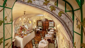 An elegant dining area with a high arched ceiling, wooden flooring, and a variety of table settings. - Boutique Hotel Campo dé Fiori (Rome)