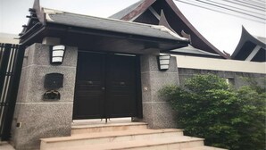 A building with a dark brown entrance, a stone facade, and a triangular roof. - Villa Xilaiwan (Ratsada)