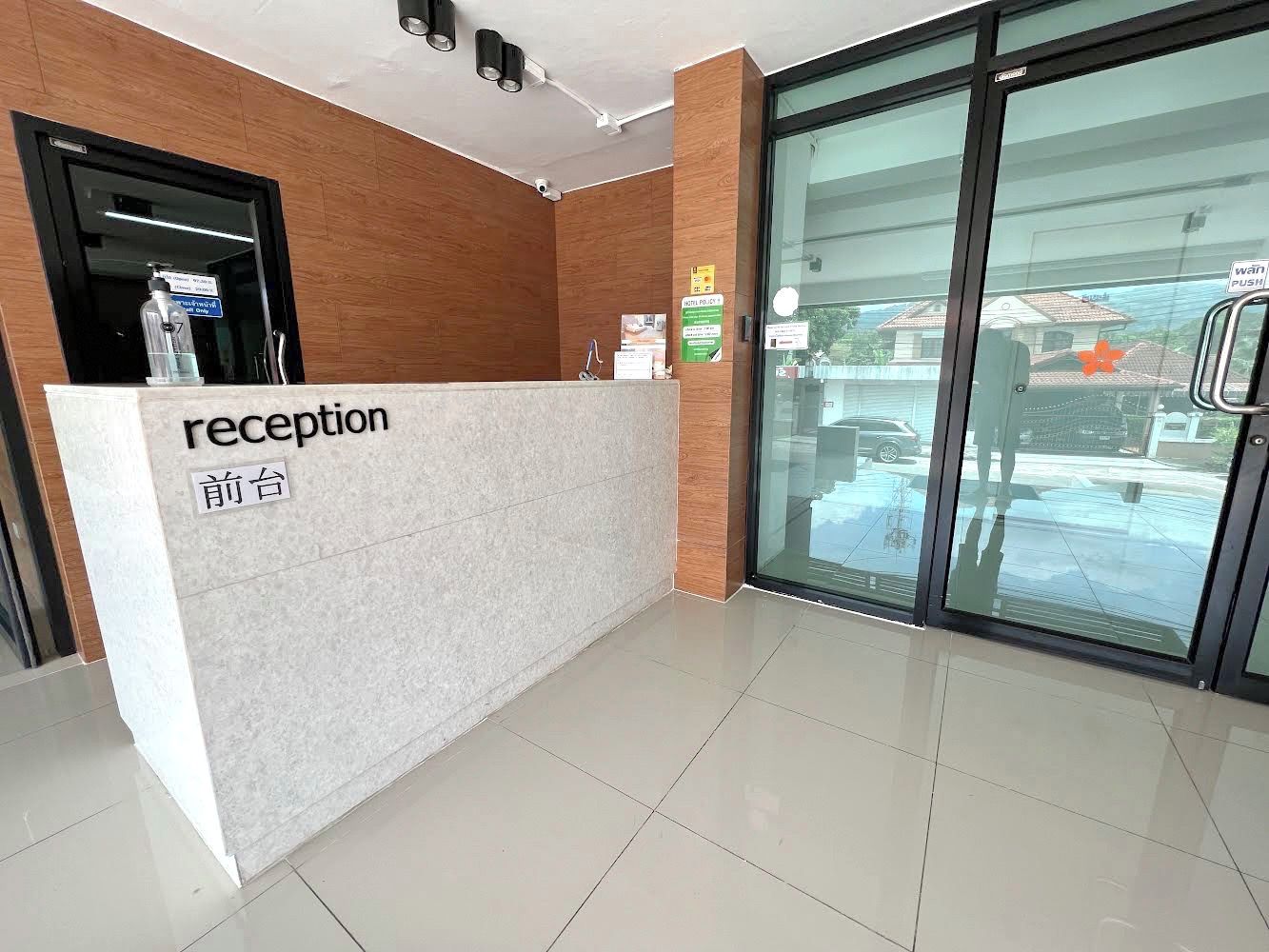 A reception desk with a sign reading "reception" and "前台" in another language, a water dispenser, and a glass door leading outside.