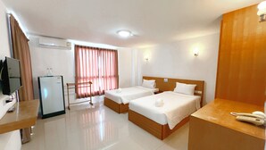 Een hotelkamer met twee bedden, een bureau met telefoon, een televisie en een koelkast.
