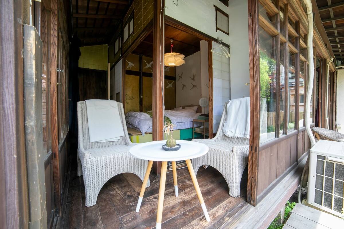 A cozy room with a wooden floor, a round table with a vase, and two wicker chairs.