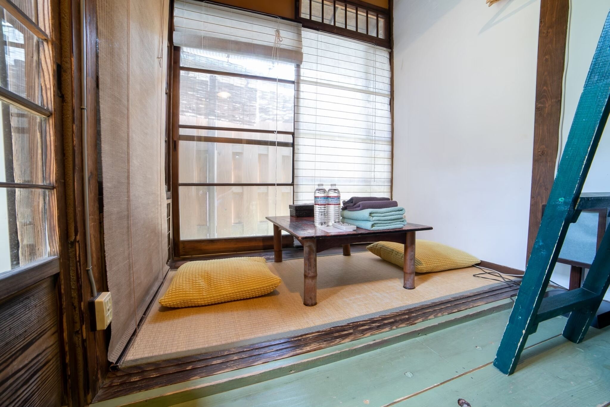 A traditional Japanese room with tatami flooring, a shoji screen, and a small table with water bottles and towels.