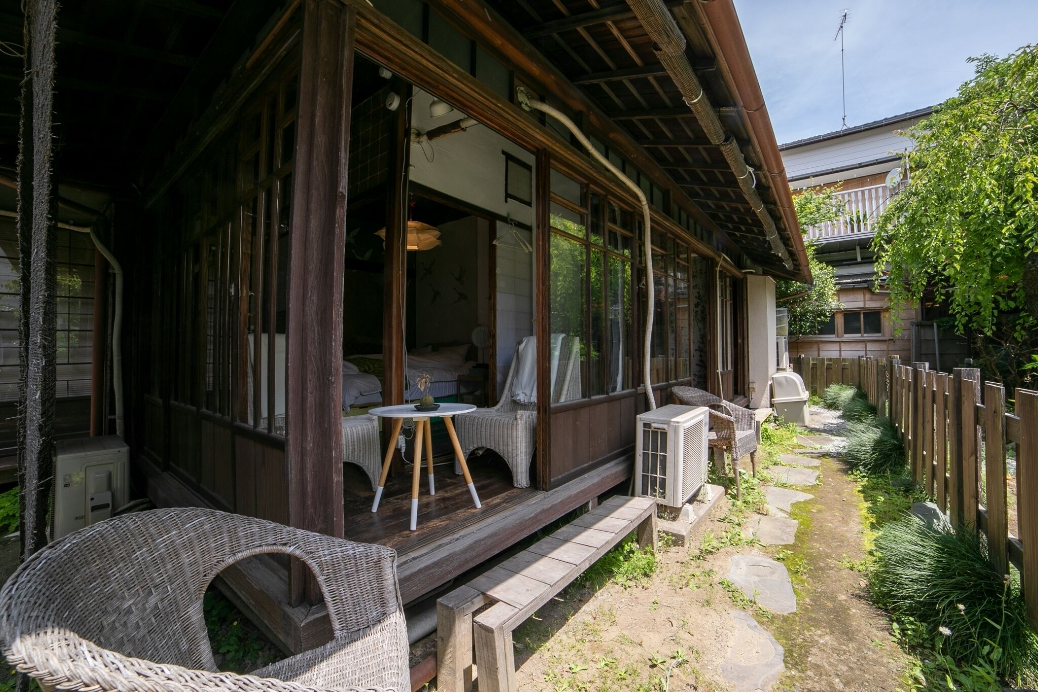 A traditional Japanese-style building with a wooden exterior, large windows, and a covered porch area with wicker furniture.