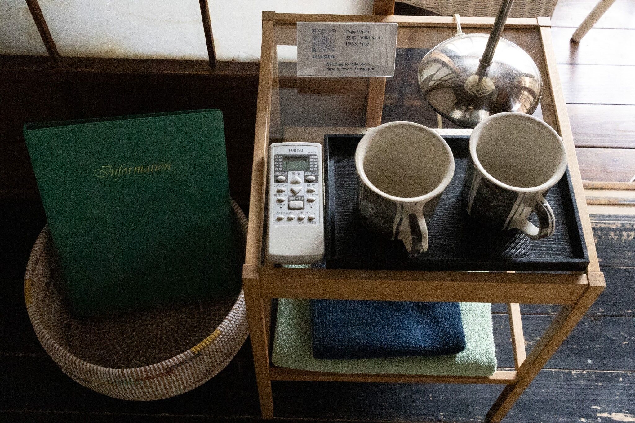A wooden table with a Fujitsu phone, two mugs, and a sign indicating free Wi-Fi and SSID.