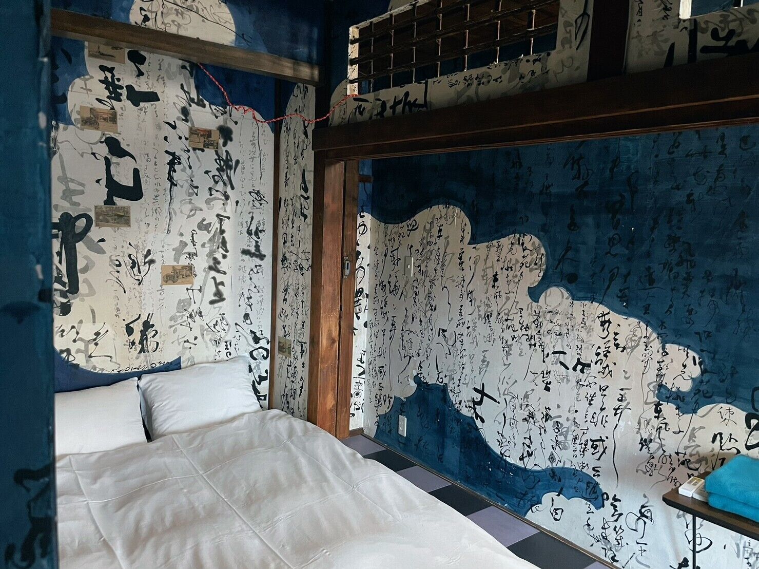 A room with a bed, a window, and walls covered in black and white graffiti.