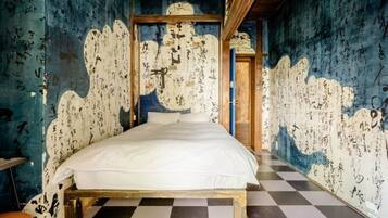 Um quarto com uma cama, piso xadrez e paredes cobertas de escritas.