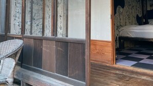 Um quarto japonês tradicional com tatames, uma cama de madeira baixa e um painel deslizante shoji com caligrafia.