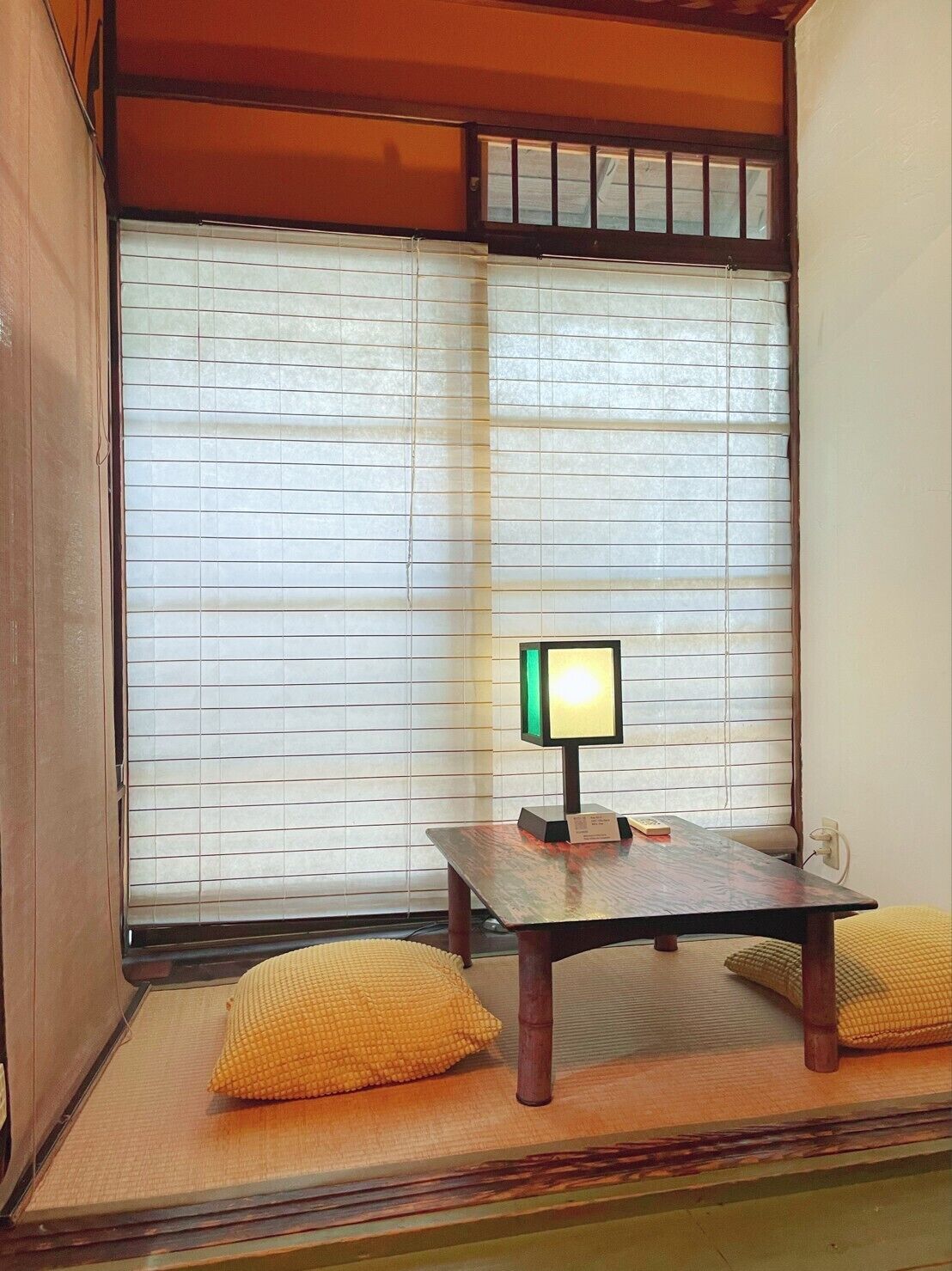 Ein traditioneller japanischer Raum mit Tatami-Boden, einem niedrigen Tisch mit Lampe und Shoji-Schiebetüren.