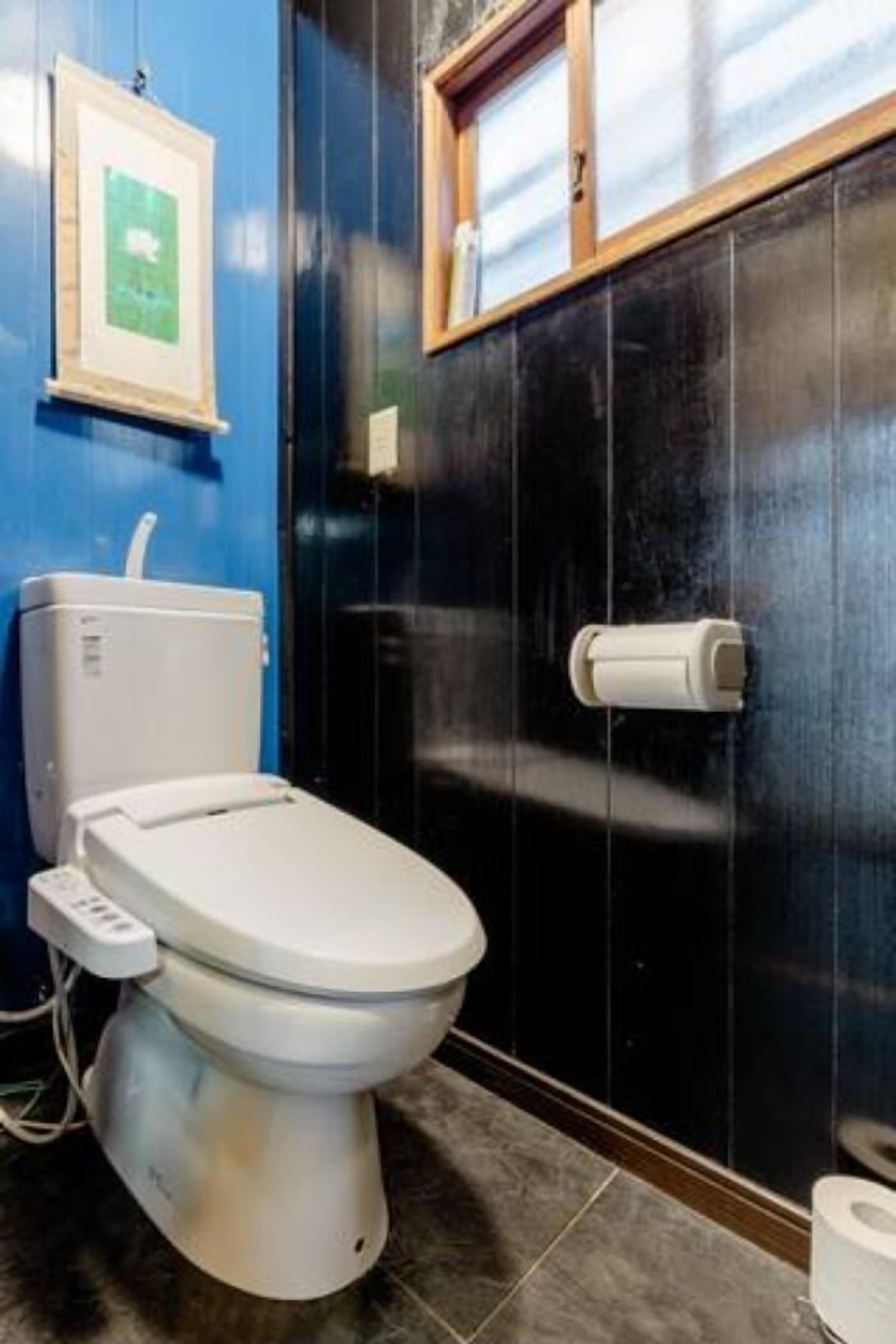 Un baño moderno con un inodoro blanco, un secador de manos y un dispensador de papel higiénico en la pared.