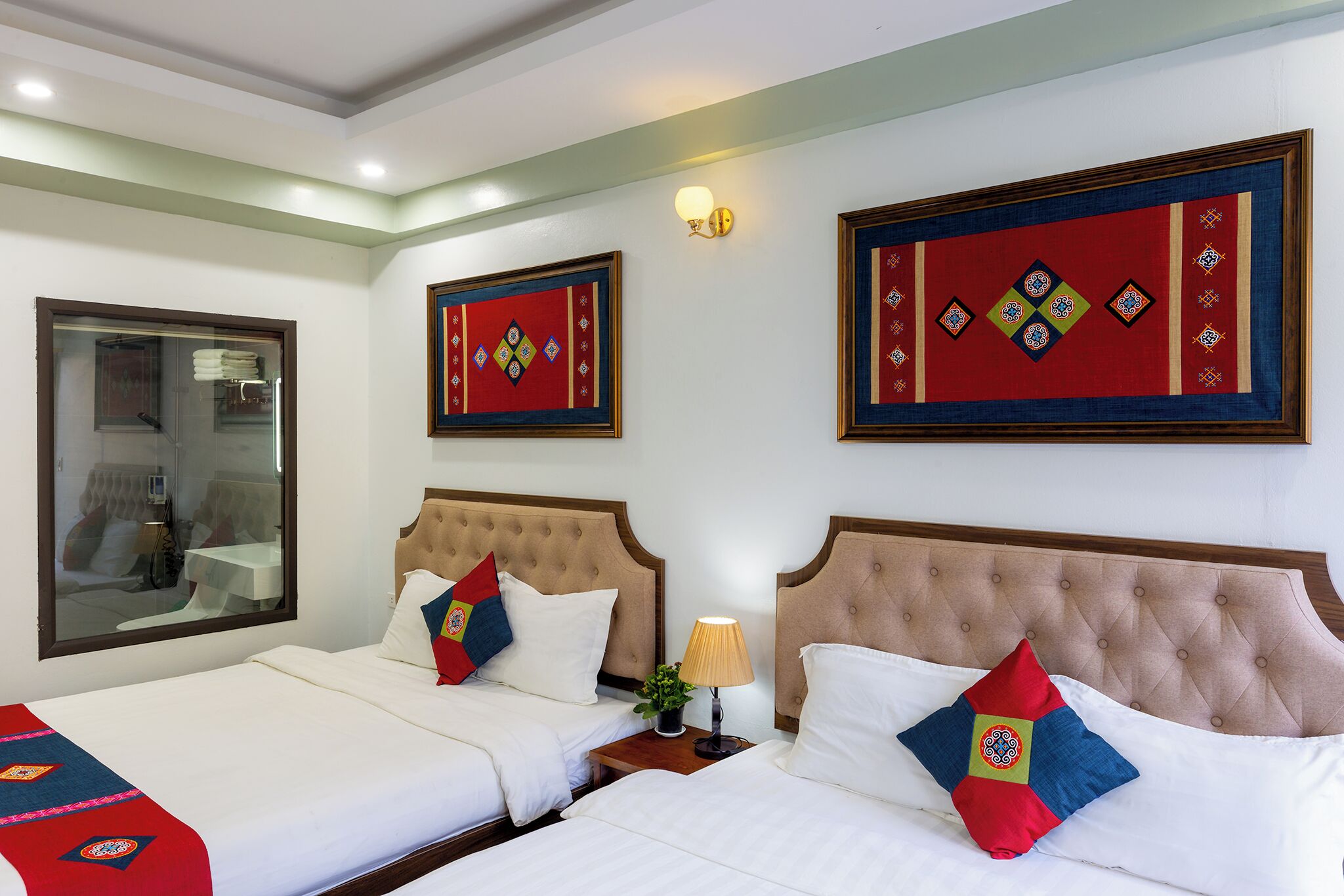 A hotel room with two beds, a large mirror, and decorative wall hangings.