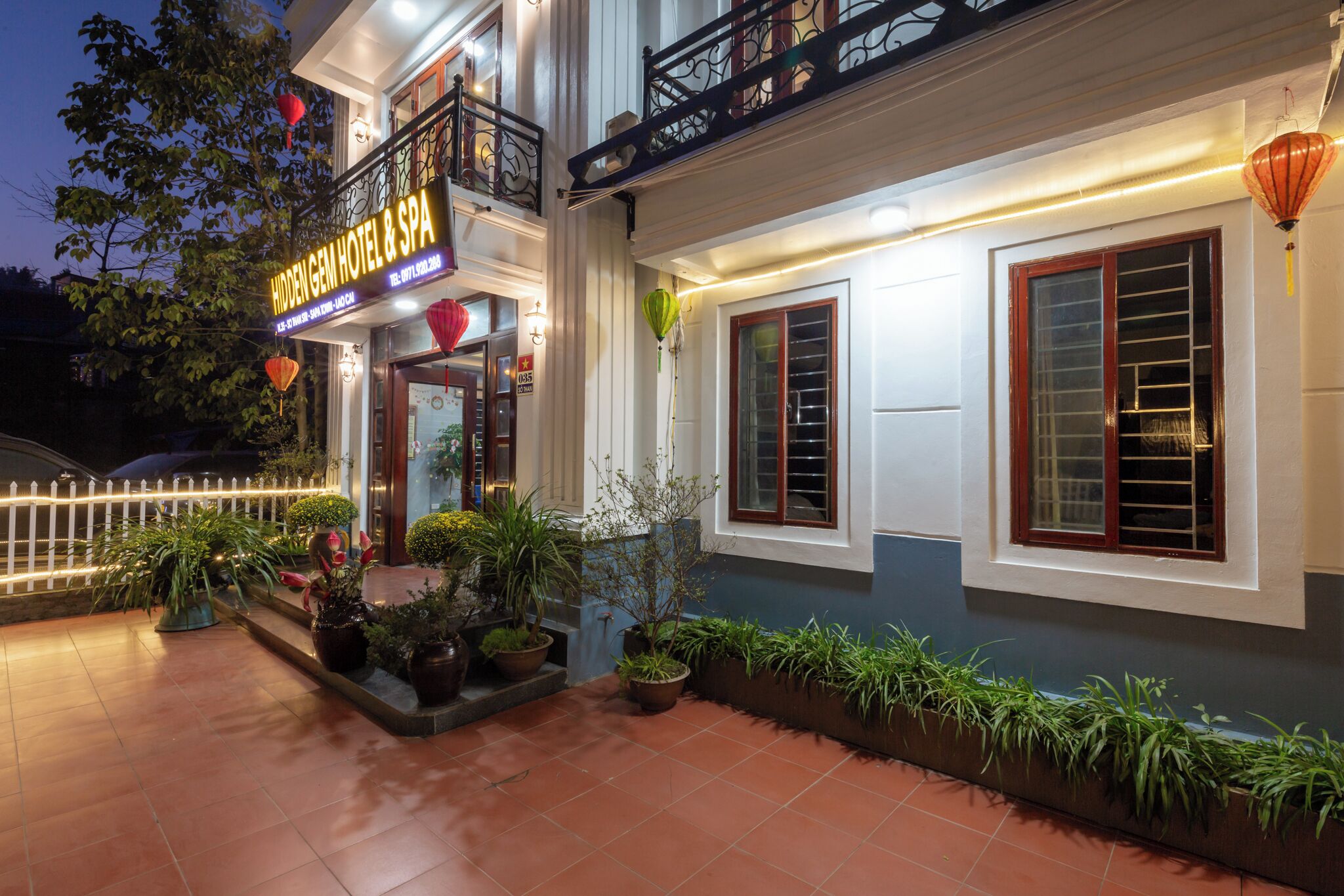 A hotel with a balcony, potted plants, and a sign.
