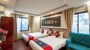 A hotel room with two beds, a large window, a sofa, and a decorative wall piece.