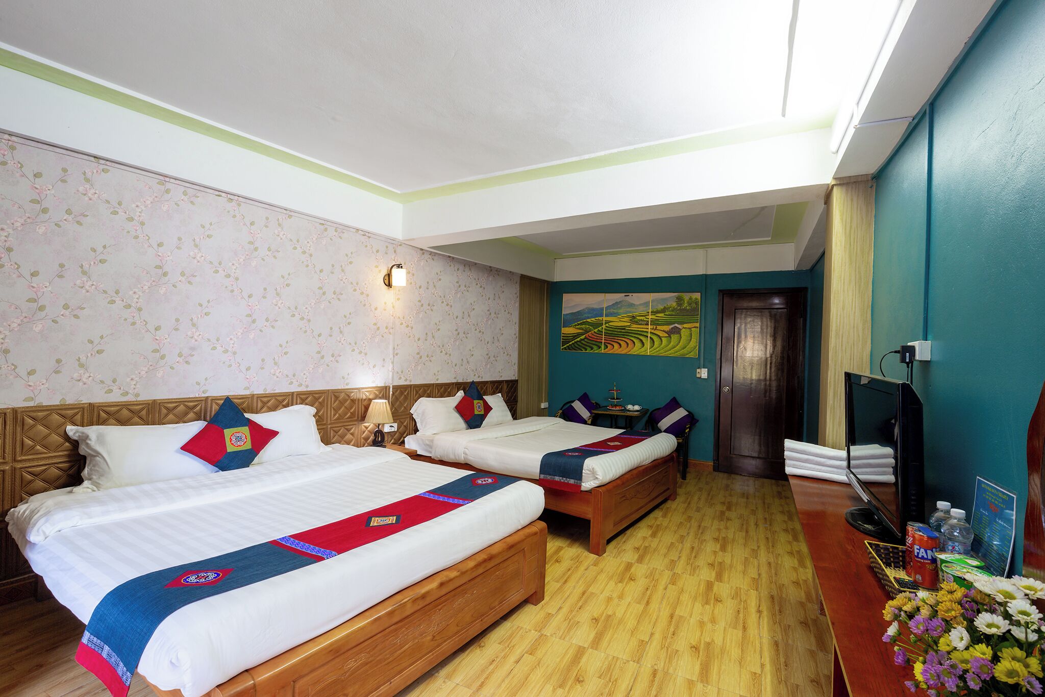 A hotel room with two beds, a desk with a computer, and a painting on the wall.