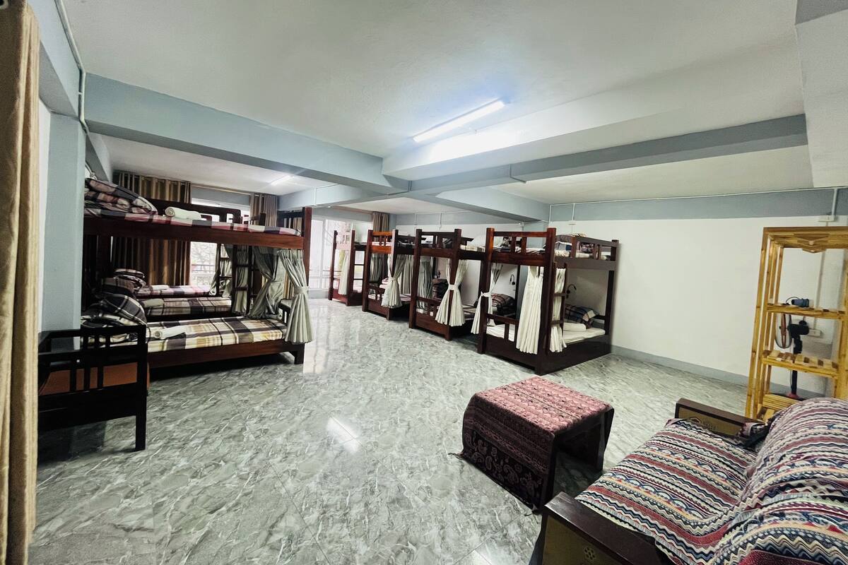 A dormitory-style room with bunk beds, a small table, and a bench.