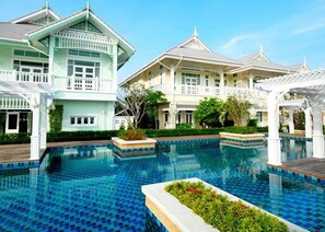 A resort with a large swimming pool, traditional architecture, and well-maintained gardens. - Moon Margo (Cha-am)