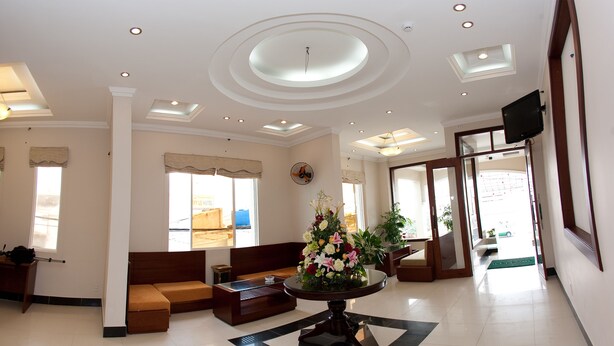 A hotel lobby with a reception desk, seating area, and a large floral arrangement. - Ocean Star Hotel (Ho Chi Minh City)