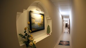 A hallway with a framed painting, a potted plant, and a floral arrangement. - Ocean Star Hotel (Ho Chi Minh City)