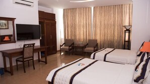 A hotel room with two beds, a desk, a television, and a dining area. - Ocean Star Hotel (Ho Chi Minh City)