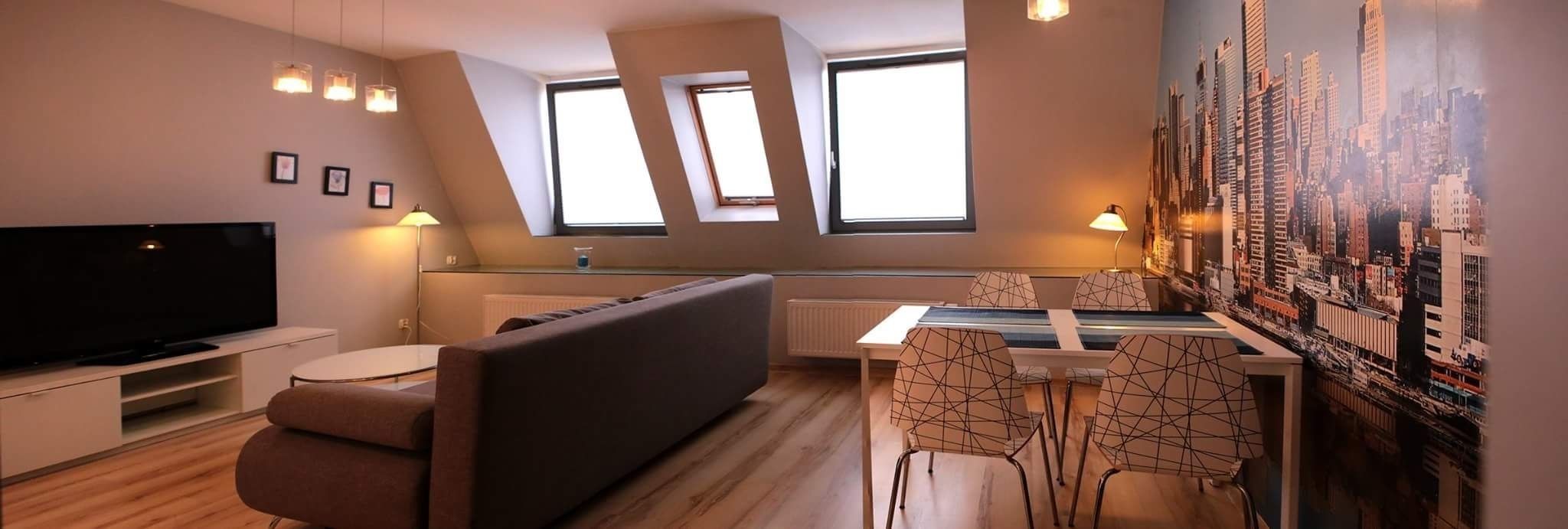 A modern living room with a flat-screen TV, a sofa, a dining table with chairs, and a cityscape mural.