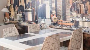 Un comedor con un mural de paisaje urbano, una mesa blanca y sillas modernas.