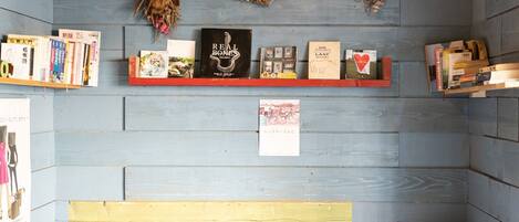 A room with a blue wooden wall, a bookshelf with books, a red shelf, and a yellow bench.
