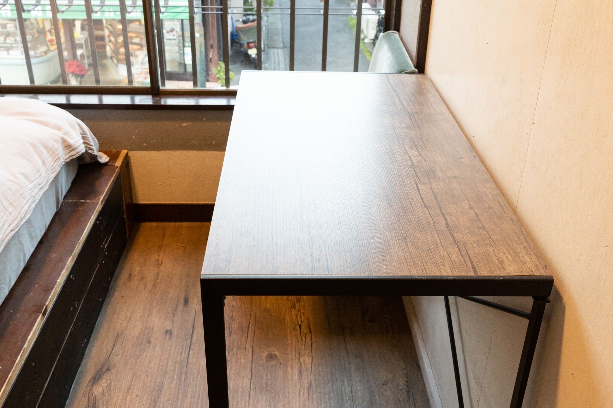 A small room with a wooden table, a bench, and a window with a view of the street.