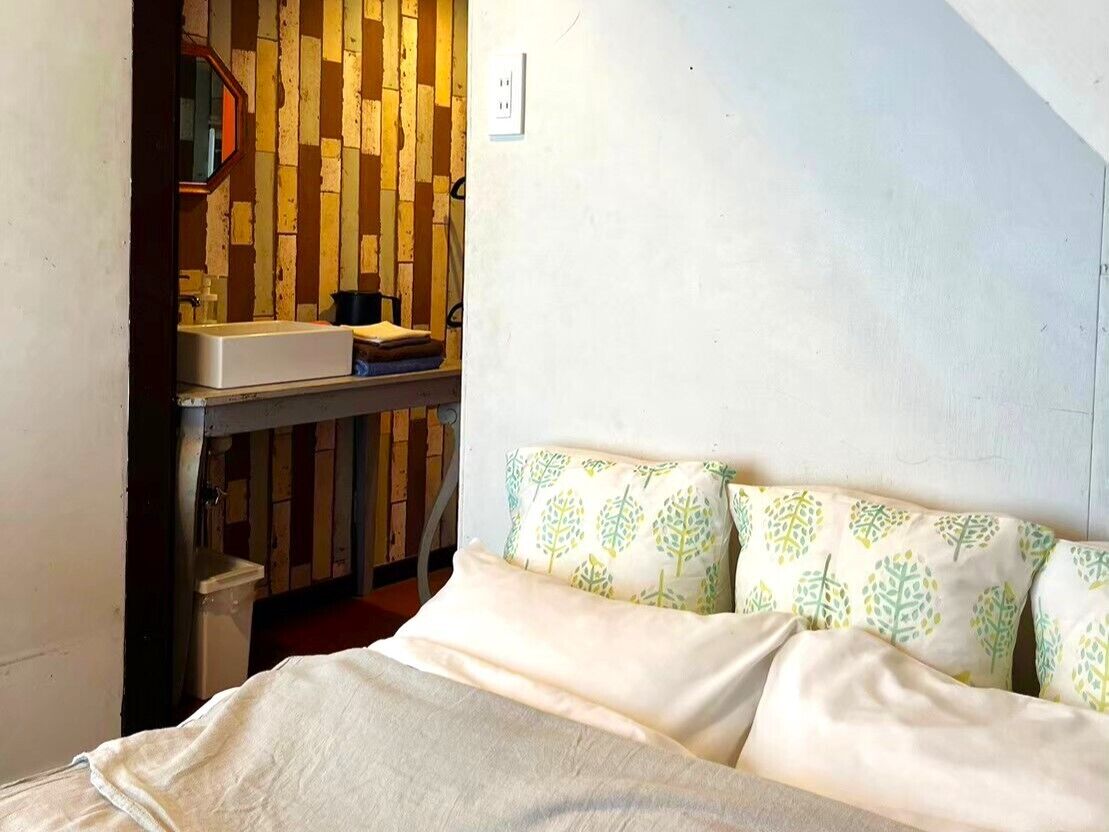 A small bedroom with a bed, a nightstand, and a wooden wall.
