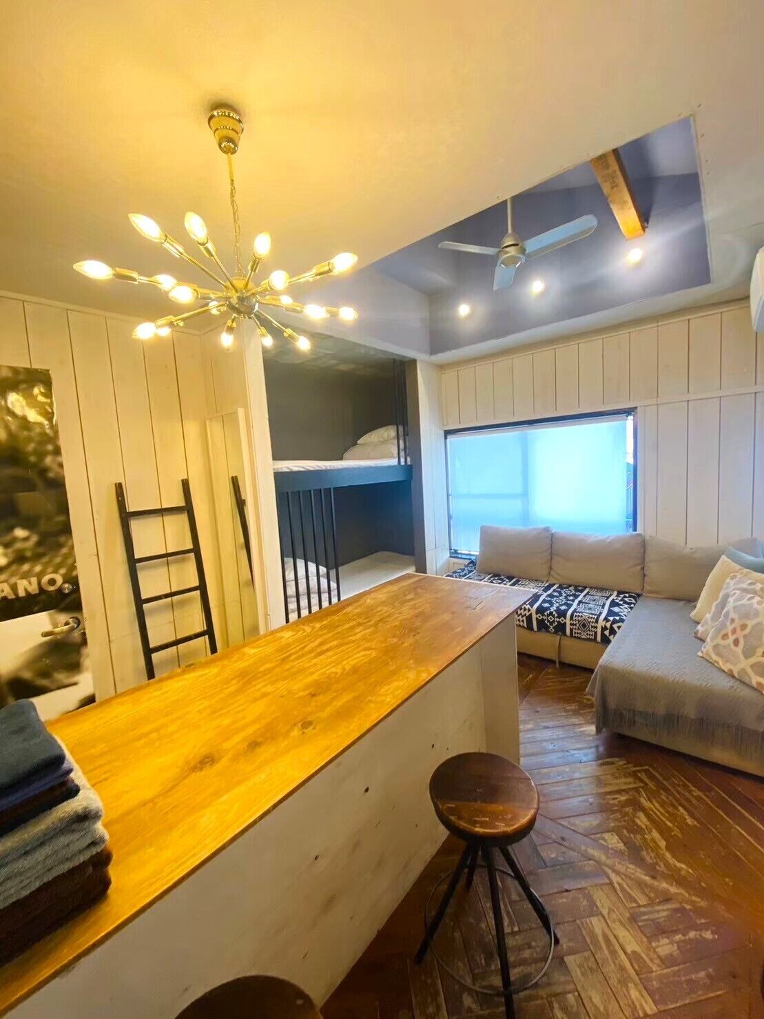 A compact living space with a kitchenette, a bunk bed, a sofa, and a dining area.