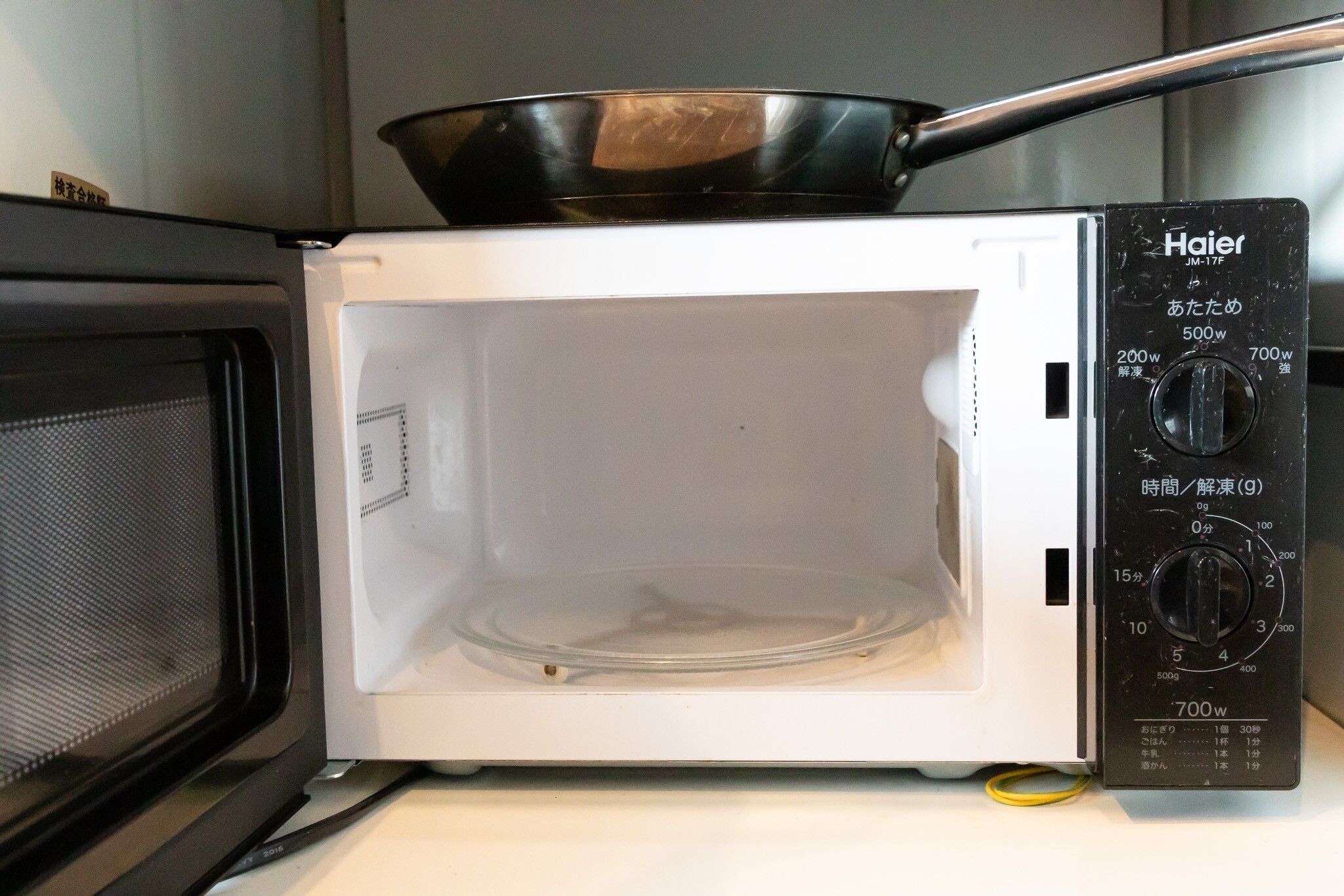 A white Haier microwave oven with a black control panel and a black cooking pot on top.
