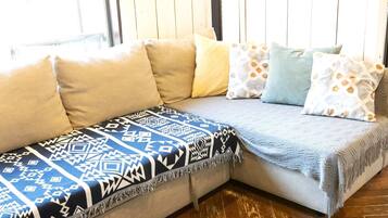A sectional sofa with patterned throw blankets and pillows in a room with wooden flooring.