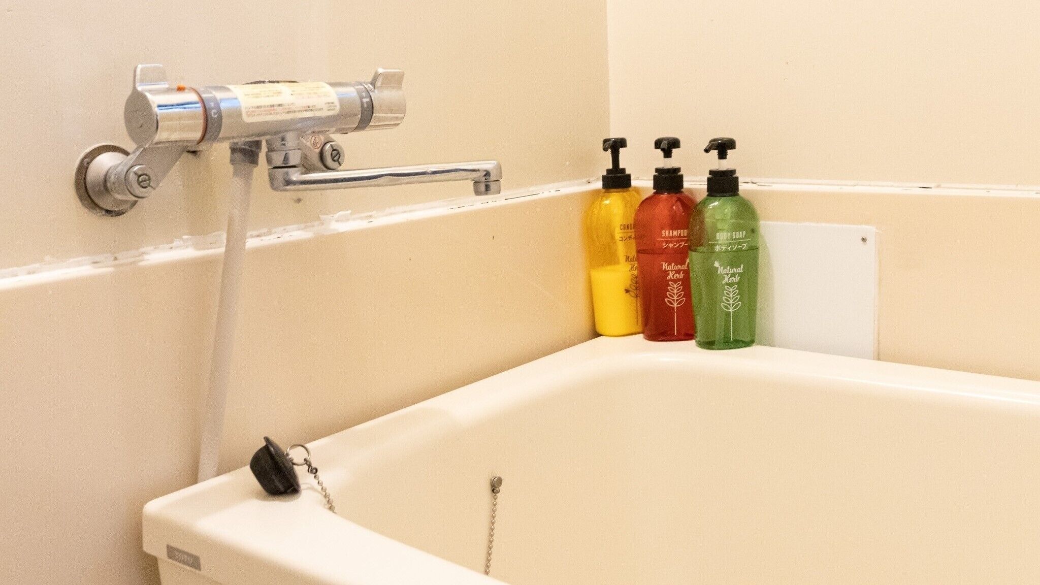 Eine Badewanne mit Wasserhahn und drei Shampoo-Flaschen.
