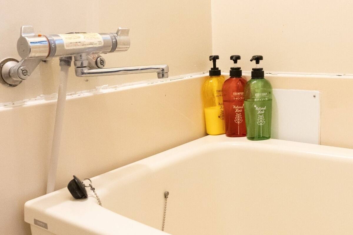 Una bañera con un grifo y tres botellas de champú.