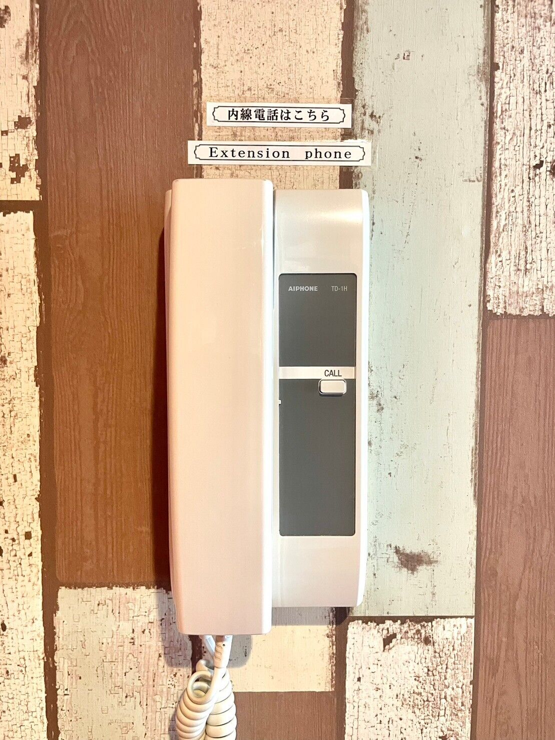 A white extension phone with a black keypad and a coiled cord.