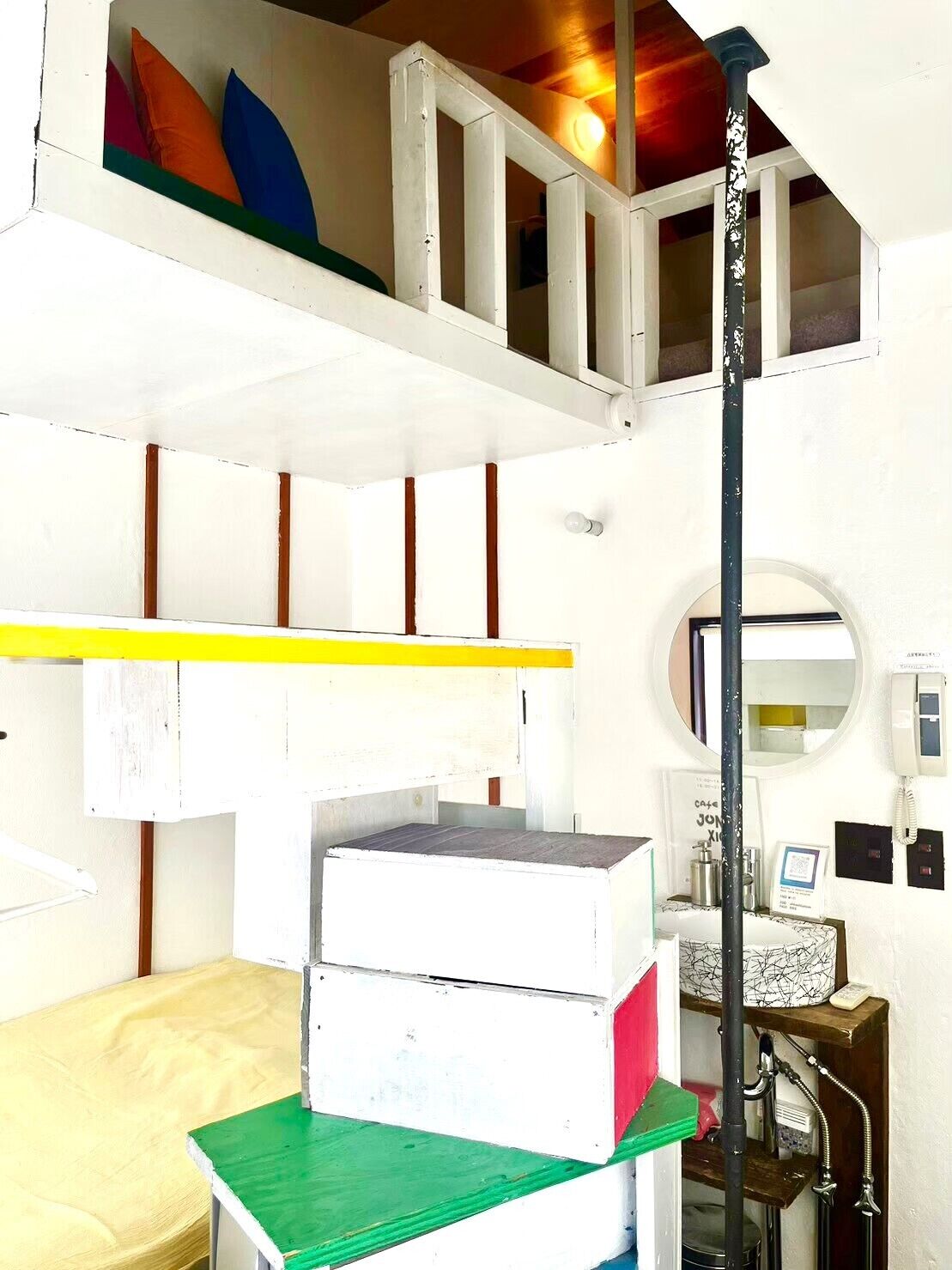 A compact room with a bunk bed, a small desk, and a mirror.