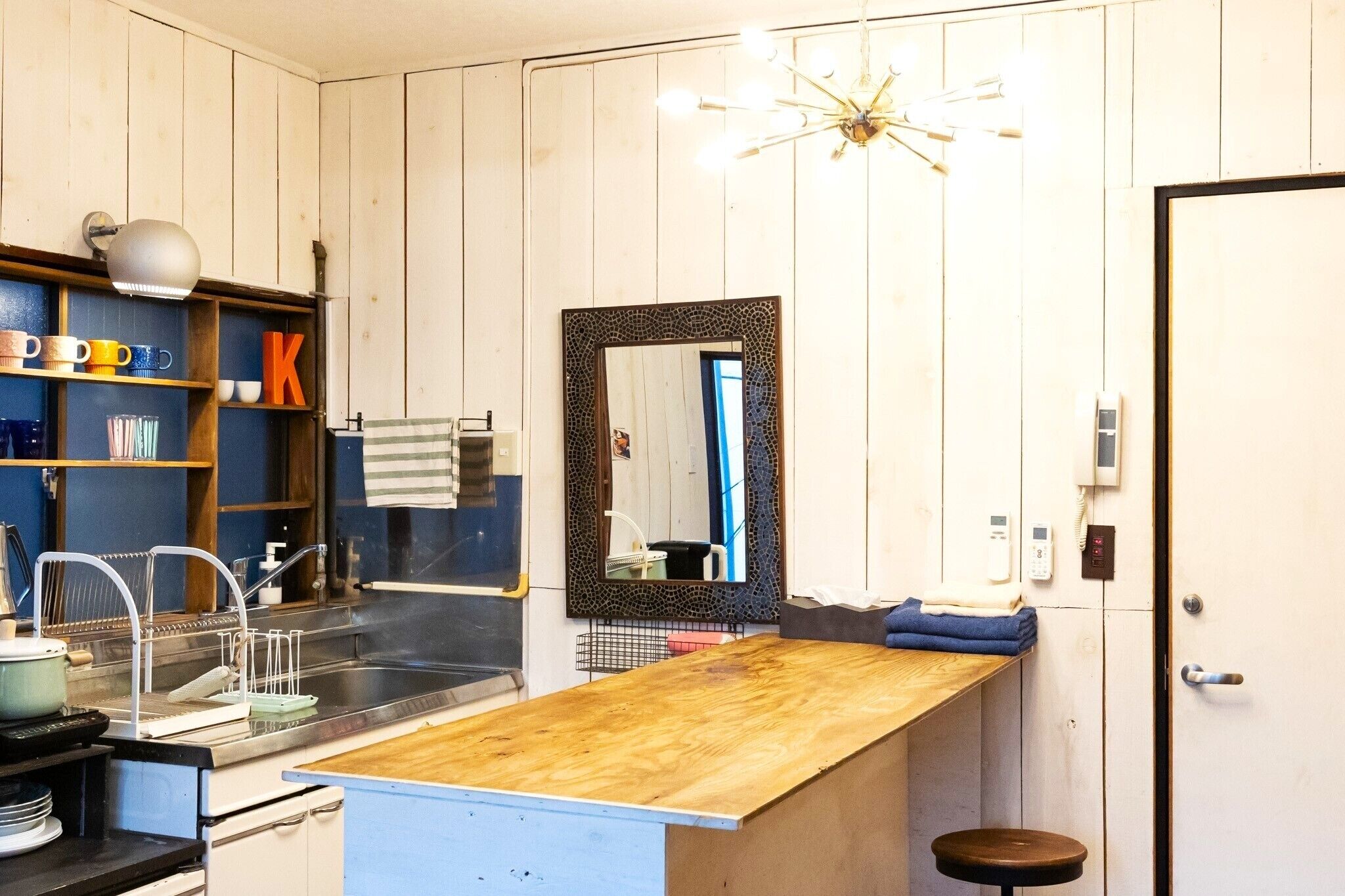 A compact kitchen with a wooden countertop, a sink, and a mirror.