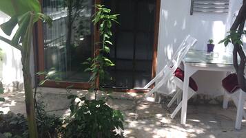 A patio area with a glass door, white chairs, a small table, and a lantern.