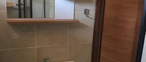 A bathroom with a white sink, a mirror, and a wooden door.