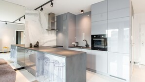 A modern kitchen with a central island, bar stools, and built-in appliances. - SUPER-APARTAMENTY International Fair (Poznan)