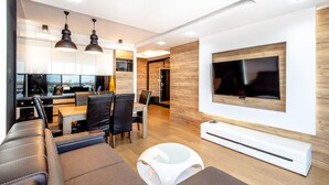 A modern living room with a sofa, a coffee table, and a TV mounted on the wall. - SUPER-APARTAMENTY International Fair (Poznan)