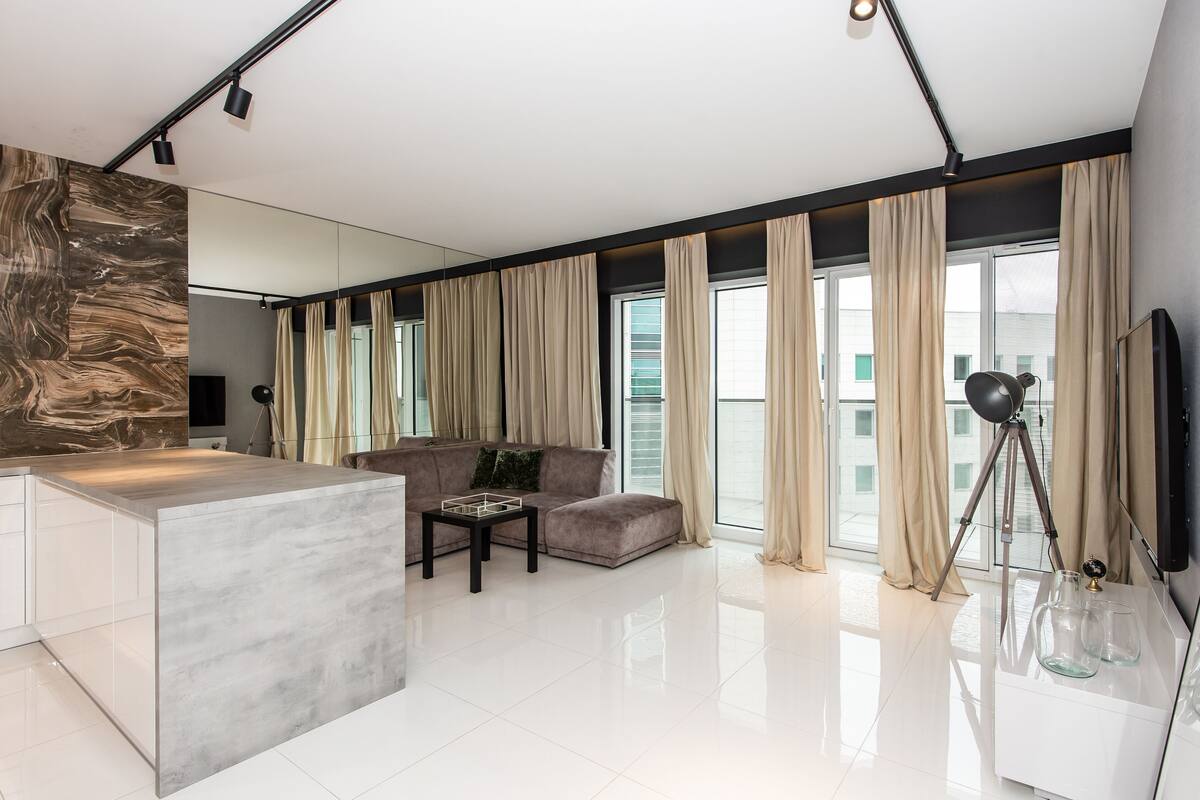 A modern living room with a marble island, a sofa, and a tripod lamp.