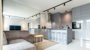 A modern kitchen with a central island, a sofa, and a small round table. - SUPER-APARTAMENTY International Fair (Poznan)