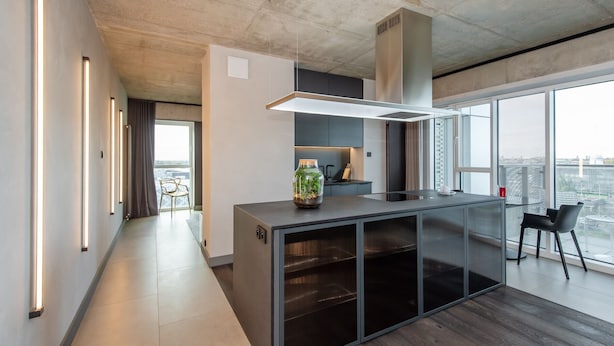 A modern kitchen with a central island, a large window, and a view of the city. - SUPER-APARTAMENTY International Fair (Poznan)