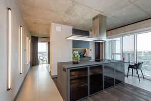A modern kitchen with a central island, a large window, and a view of the city. - SUPER-APARTAMENTY International Fair (Poznan)