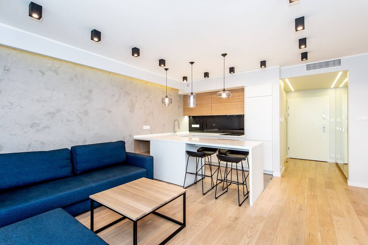 A modern kitchen with a central island, bar stools, and pendant lighting.