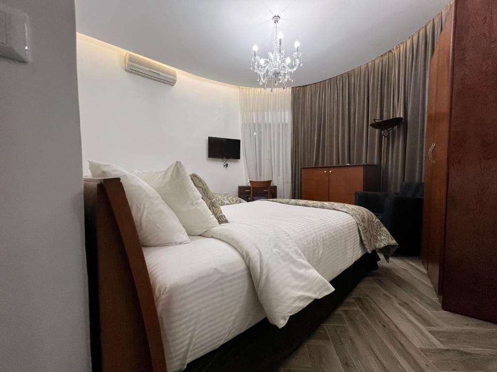 Un dormitorio con cama, televisor, candelabro y armario.