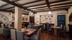 A restaurant with wooden tables and chairs, a high ceiling with exposed beams, and decorative plates on the walls.