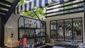 A bar area with shelves of liquor bottles, a counter with glasses and a cash register, and a decorative mirror.