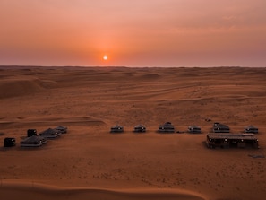 A desert landscape with multiple yurts and tents arranged in a row, suggesting a campsite or accommodation area.