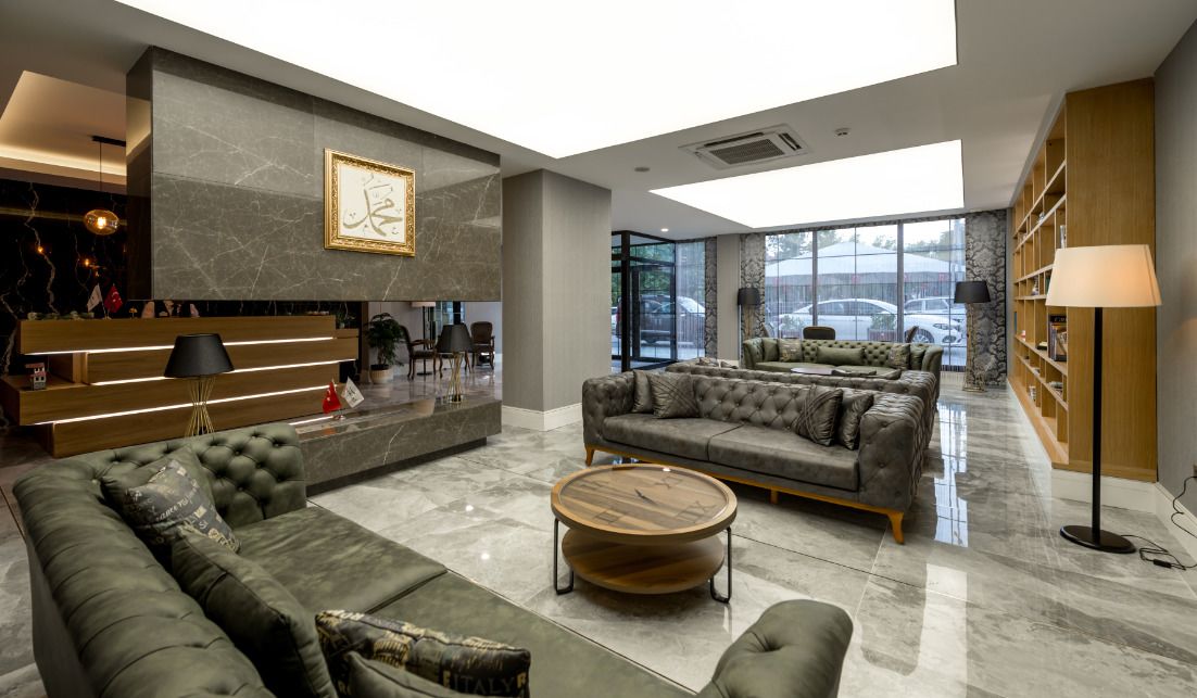 A spacious lobby with a marble floor, a reception desk, a sofa area, and a bookshelf.